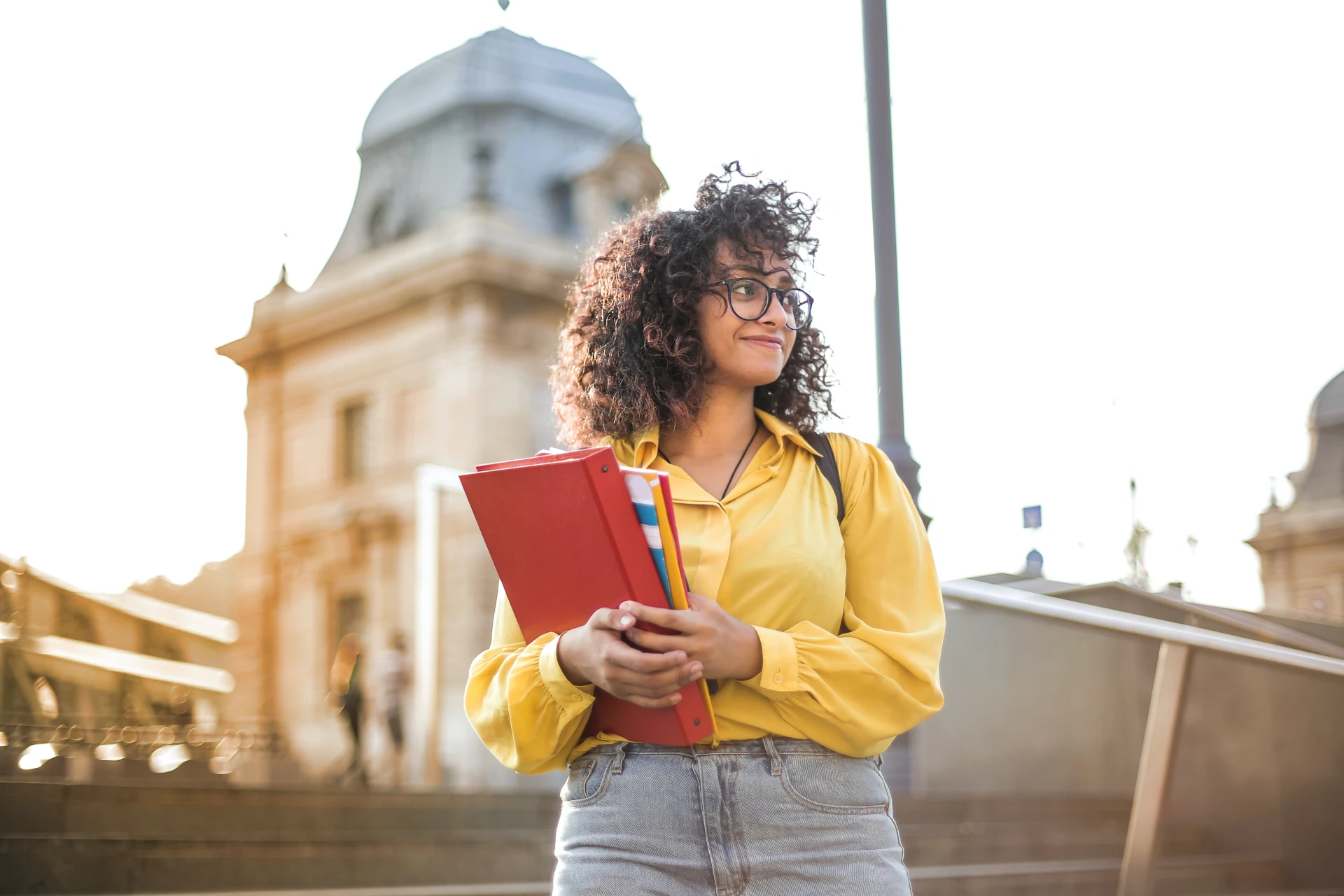 Aluna segurando materiais de estudo em ambiente universitário